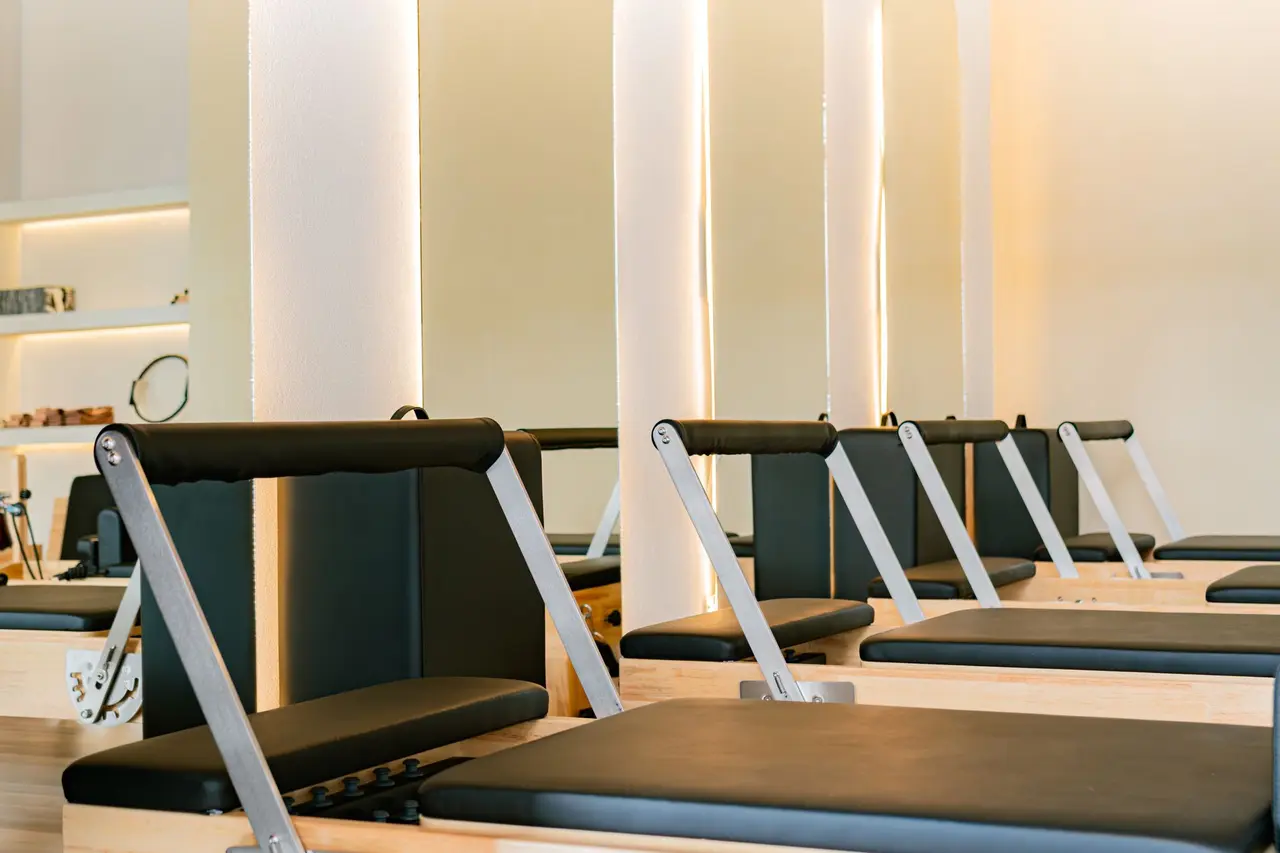 A quiet Pilates studio with a row of reformers in warm light